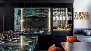 A modern kitchen with a marble island, built-in appliances, and a seating area with a sofa and chairs. - Luxury Paddington Townhouse (Darlinghurst)
