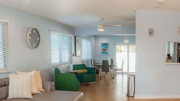 A modern living room with a sectional sofa, a glass coffee table, and a dining area with a table and chairs. - Luxury Pool Home, Near the Beach and Cruise Port (Dania Beach)