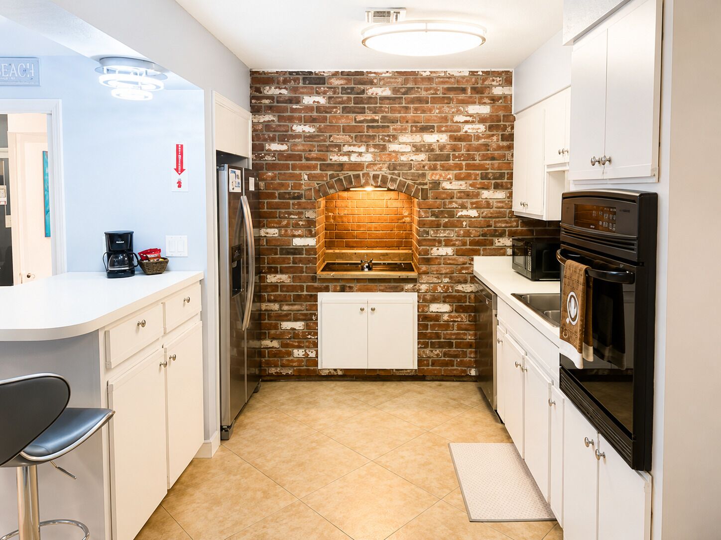 A compact kitchen with white cabinetry, a brick backsplash, and a built-in oven.