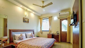A hotel room with a large bed, a ceiling fan, a TV mounted on the wall, and a window with curtains. - Eufregina Resort & Spa (Cavelossim)