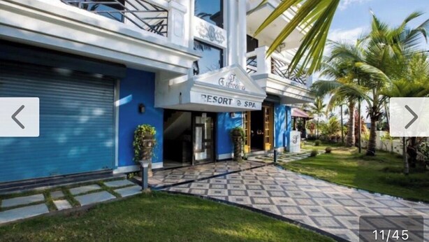 A resort with a blue facade, a sign reading "Resort & Spa," and a paved entrance area with palm trees. - Eufregina Resort & Spa (Cavelossim)
