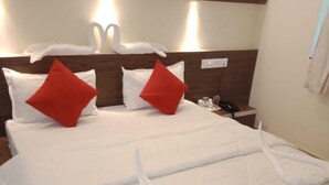A hotel room with a neatly made bed, two red pillows, a bedside phone, and a wall-mounted light fixture. - Eufregina Resort & Spa (Cavelossim)