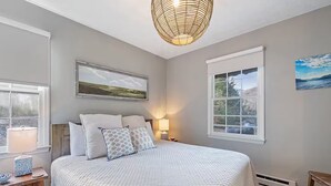 Ein Schlafzimmer mit einem großen Bett, einem Nachttisch, einer Lampe und einem Fenster mit Blick.