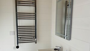 Un baño con lavamanos blanco, un espejo y un perchero para toallas.