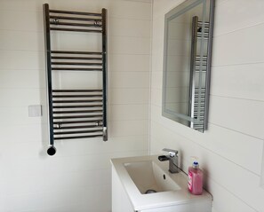 A bathroom with a white sink, a mirror, and a towel rack.