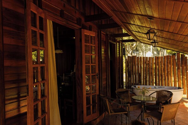 Una cabaña de madera con un jacuzzi, sillas de mimbre y una mesa.