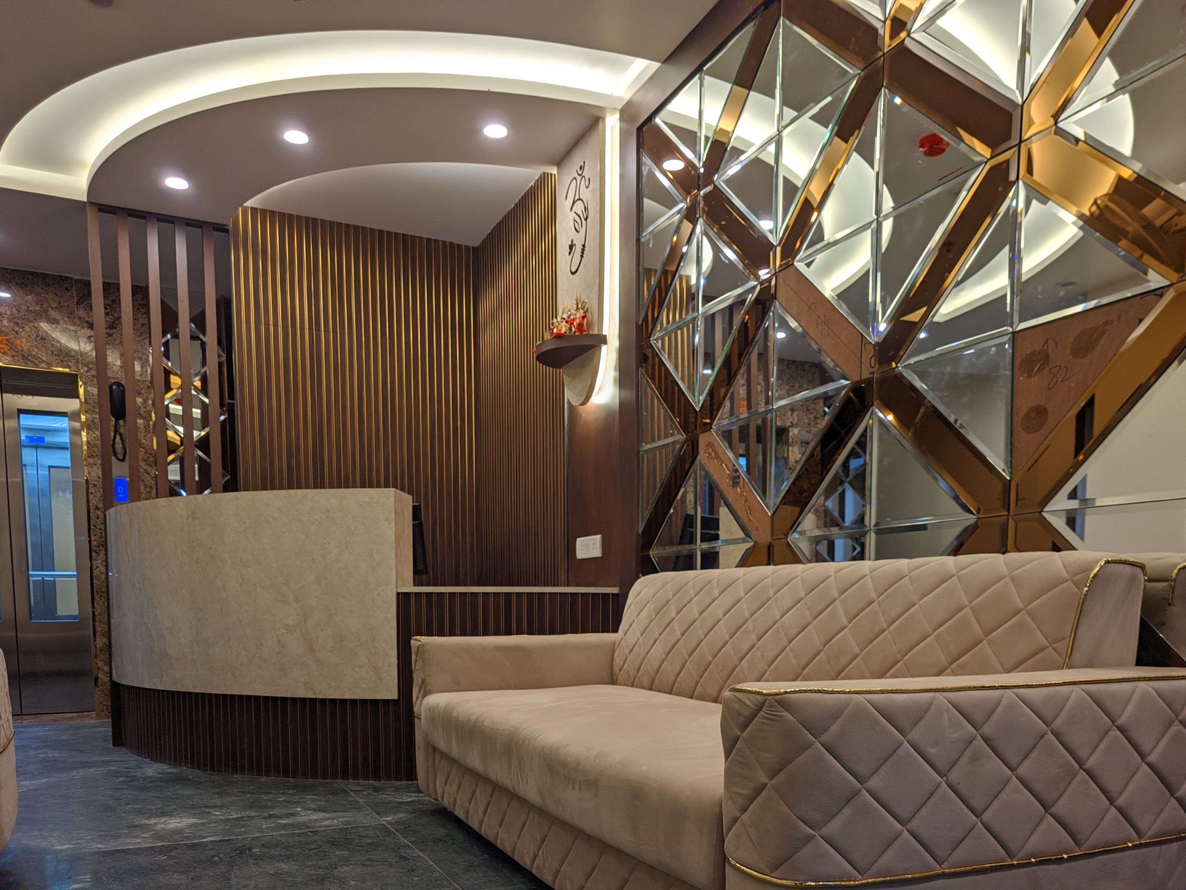 A modern reception area with a reception desk, a sofa, and a decorative wall with geometric patterns.