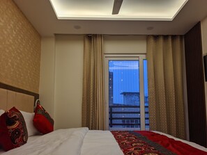 Une chambre d’hôtel avec un lit, une fenêtre avec des rideaux et une vue sur un bâtiment à l’extérieur.
