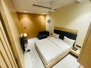 Ein Hotelzimmer mit Bett, Nachttisch, Lampe und Deckenventilator.
