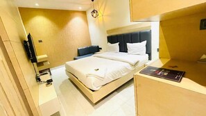 Ein modernes Hotelzimmer mit einem Bett, einem Schreibtisch, einem Sessel und einem Fernseher.