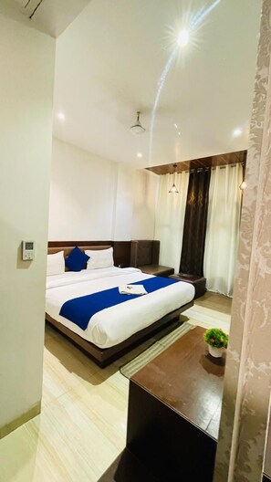 A hotel room with a bed, bedside table, lamp, and a small potted plant. - Hotel Sun Park Bhopal (Bhopal)