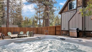 En baghave med jacuzzi, træterrasse og grill.
