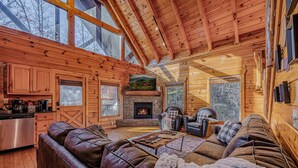 A log cabin interior with a fireplace, leather sofas, and a kitchen area. - Labor Day & Fall Getaway, Epic Mountain Views, Hot Tub, Near Dollywood (Sevierville)
