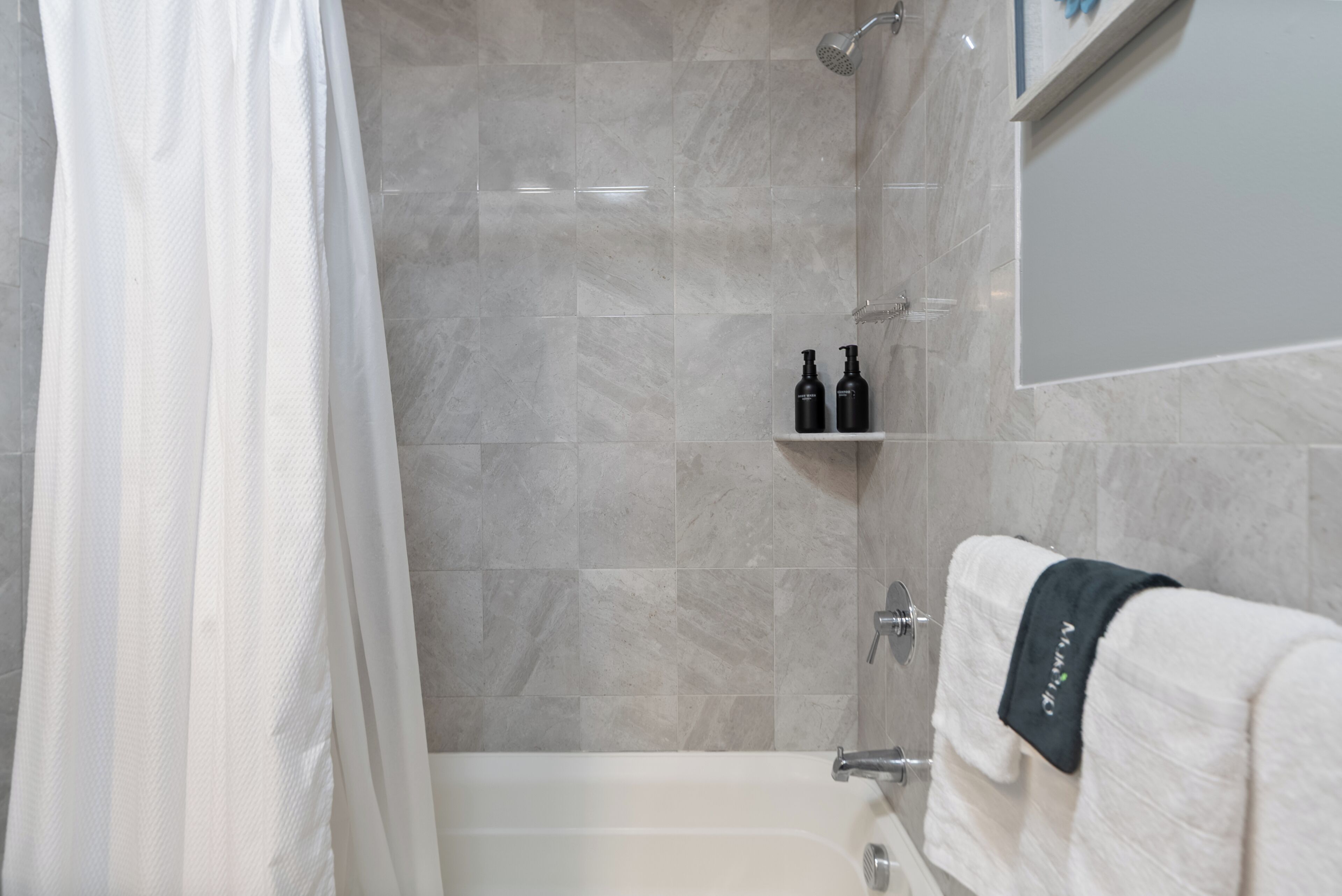 Une salle de bain moderne équipée d’une baignoire, d’une douche et d’un porte-serviettes.