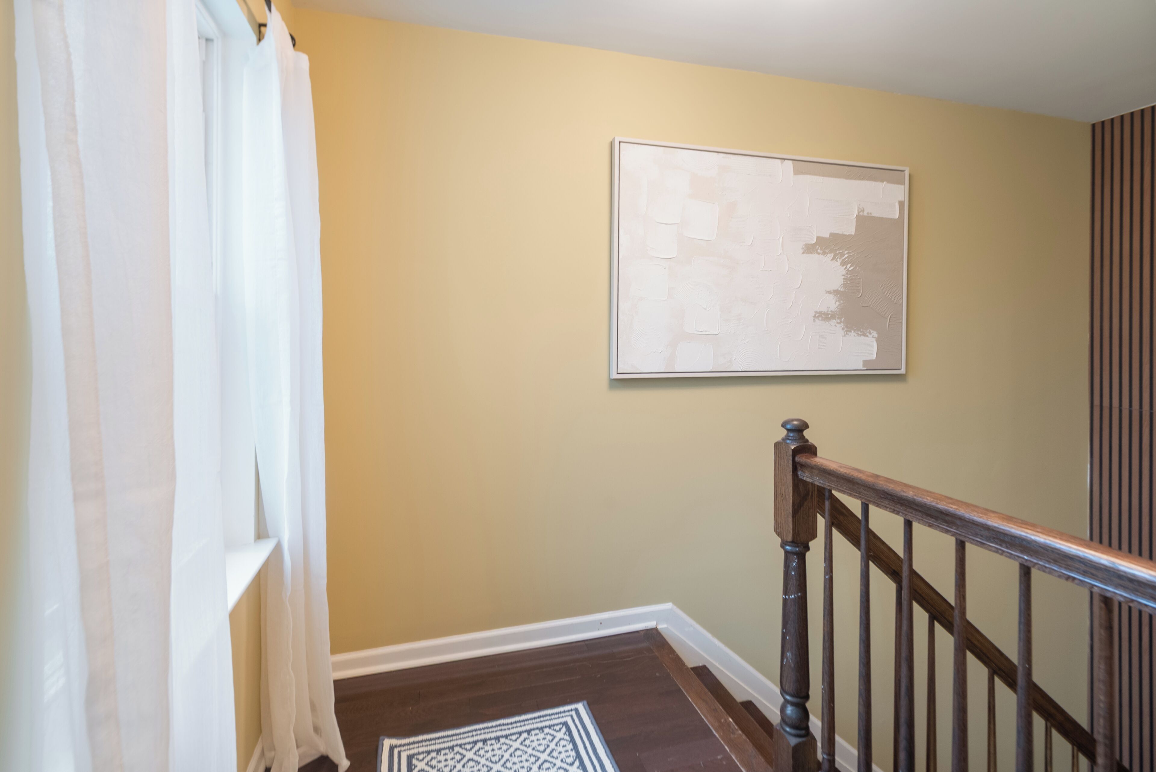 A staircase with a wooden handrail and a patterned rug at the bottom.