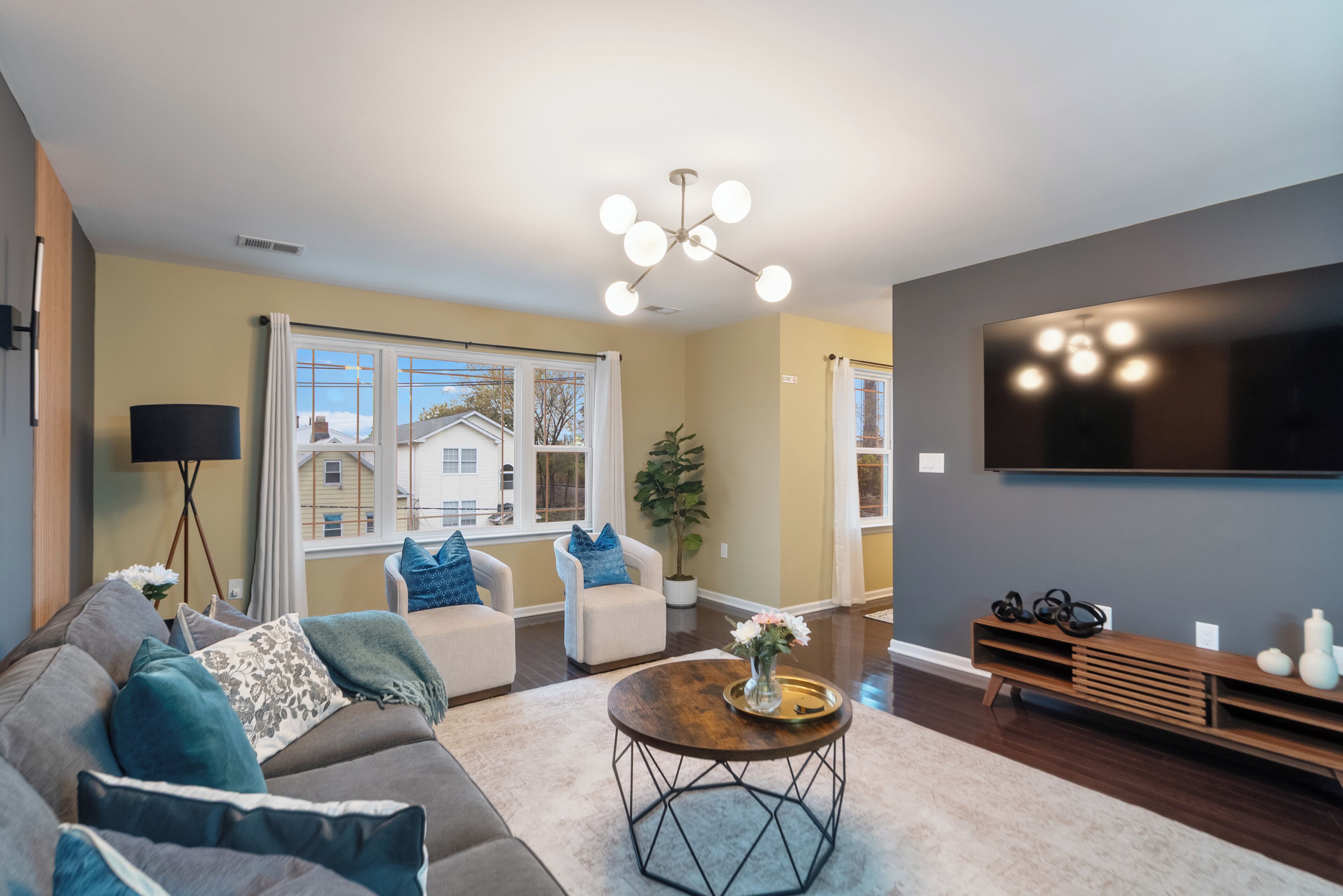 A modern living room with a sofa, armchairs, a coffee table, and a TV.