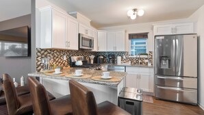 A modern kitchen with white cabinets, stainless steel appliances, and a central island with bar stools.