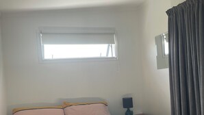 A bedroom with a bed, a window, a nightstand, and a lamp.