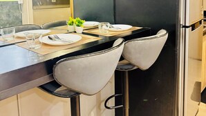 A modern kitchen with a dining table set for two, equipped with chairs, plates, cutlery, and glasses. - Twin Bed Near Airport, Mall of Asia, (Pasay City)