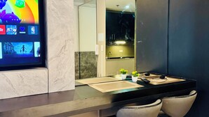 A modern bathroom with a large mirror, a vanity with a black countertop, and two bar stools. - Twin Bed Near Airport, Mall of Asia, (Pasay City)