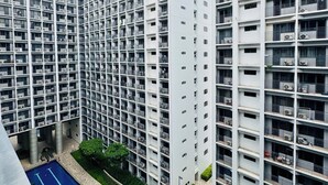 A high-rise residential building with multiple balconies, a central courtyard with a swimming pool, and a flat roof. - Twin Bed Near Airport, Mall of Asia, (Pasay City)
