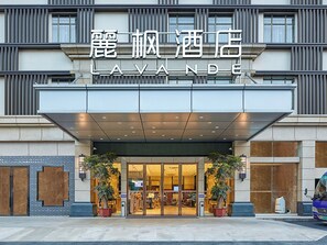 A hotel entrance with a modern facade, large glass doors, and potted plants. - Lavande International Hotel Guangzhou Baiyun International Airport Renhe Metro Station Branch (Guangzhou)