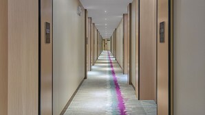 A hotel hallway with wooden paneling, numbered doors, and a carpet with a purple stripe. - Lavande International Hotel Guangzhou Baiyun International Airport Renhe Metro Station Branch (Guangzhou)
