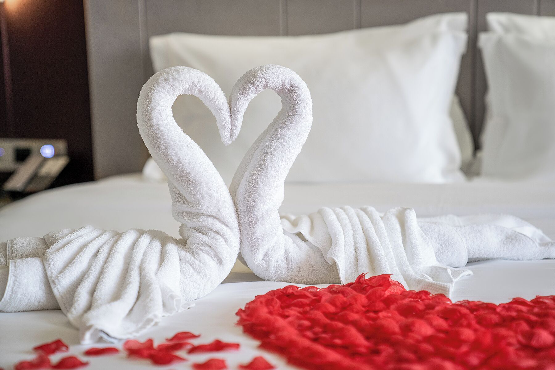 Un letto con cuscini bianchi e un'accogliente disposizione di asciugamani a forma di cuore.