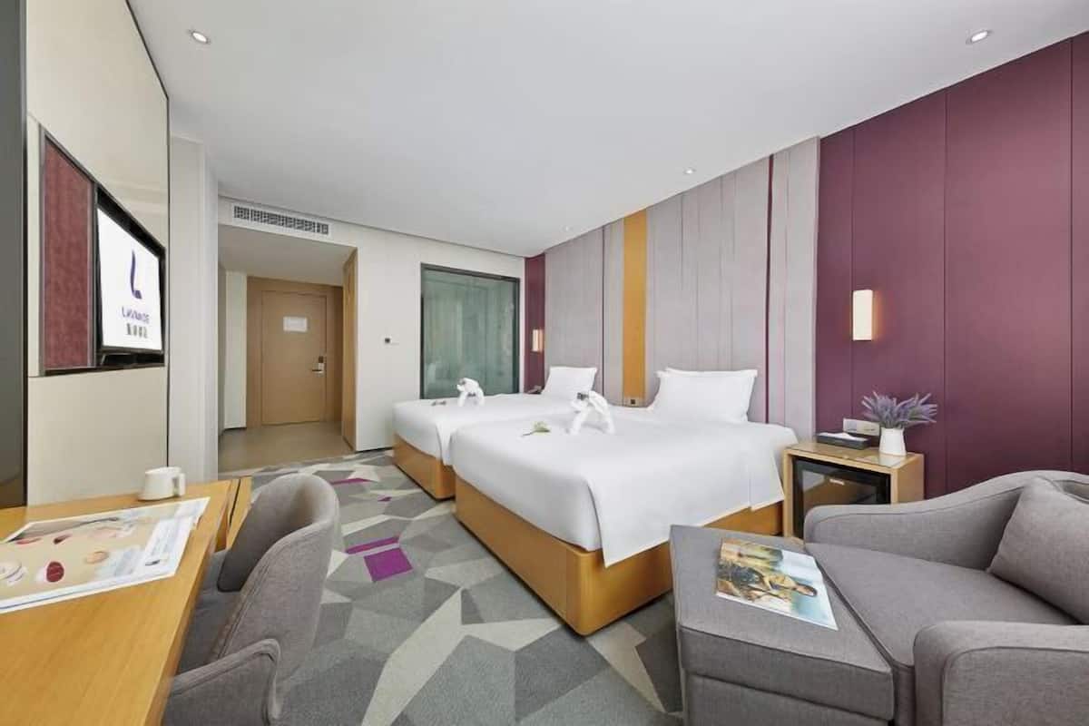Quarto de hotel com uma cama, duas mesas de cabeceira, uma escrivaninha e um sofá.