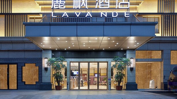 A hotel entrance with a modern facade, large glass doors, and potted plants. - Lavande International Hotel Guangzhou Baiyun International Airport Renhe Metro Station Branch (Guangzhou)