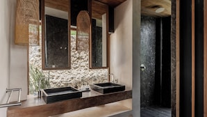 A modern bathroom with two sinks, a stone wall, and a wooden floor. - Villa Odeon (Ceningan Island)
