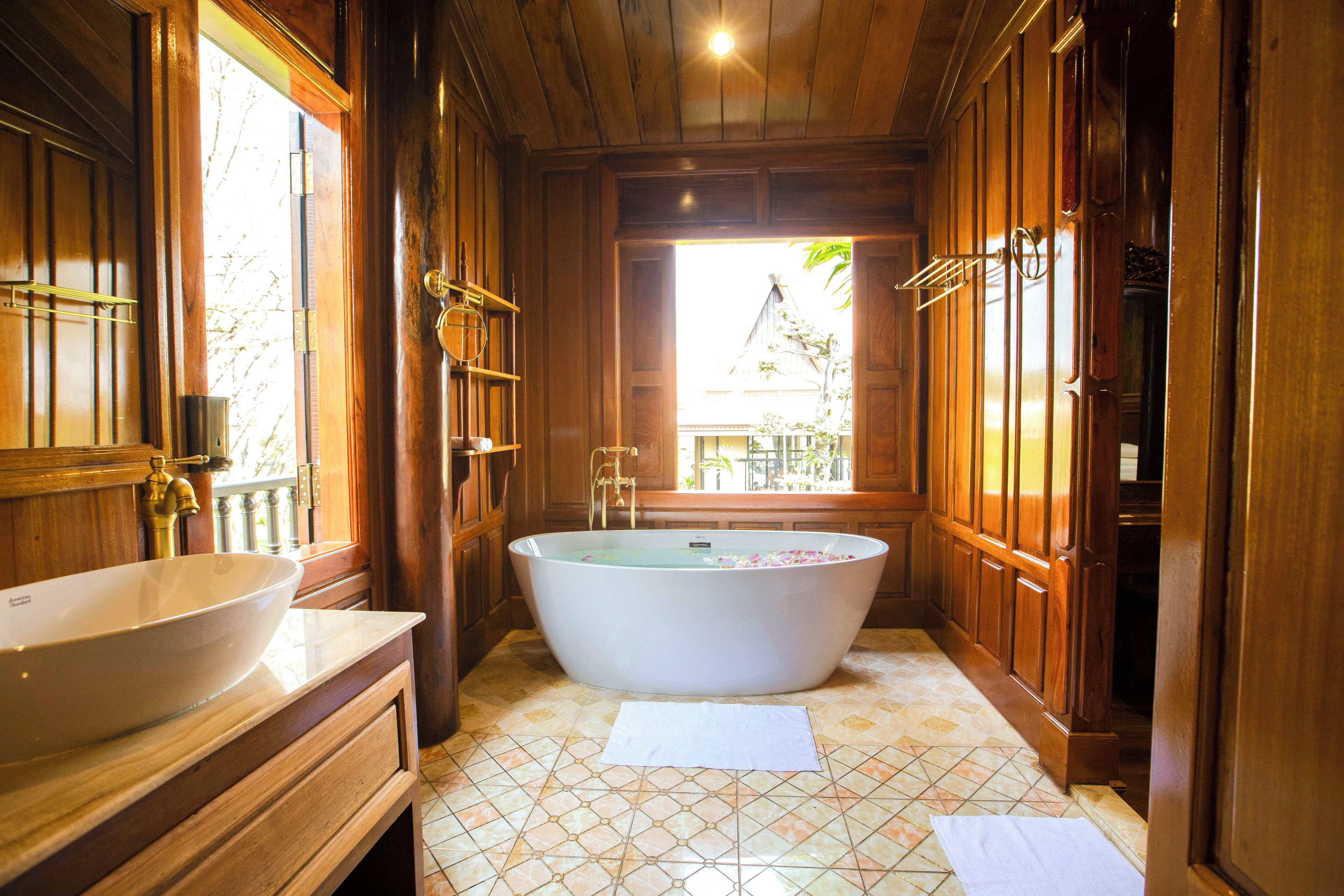 Un baño con una bañera independiente, un lavamanos grande y muebles de madera.