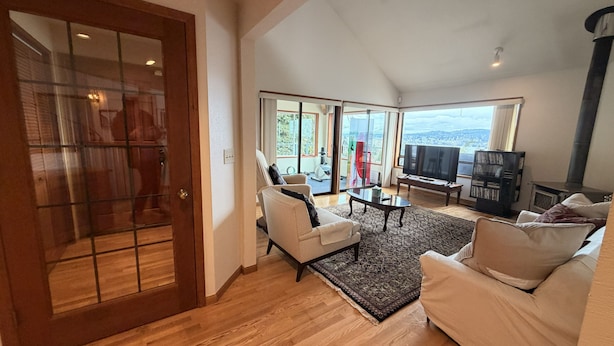 Un amplio salón con un ventanal grande, televisor y chimenea.