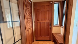 Un pasillo con suelo de madera, una puerta de madera y un banco.