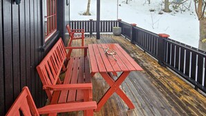 A wooden deck with red benches and a table, surrounded by a black railing. - Nice home in Rendalen with house a panoramic view (Rendalen)
