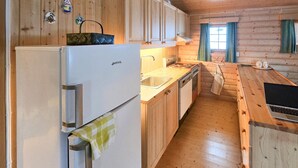 A compact kitchen with wooden cabinets, a refrigerator, a sink, and a stove. - Nice home in Rendalen with house a panoramic view (Rendalen)