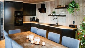 Een moderne keuken met donkere kastjes, een houten kookeiland met een spoelbak, en een eethoek met een houten tafel en blauwe stoelen.