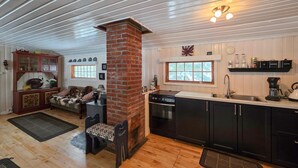 A cozy kitchen with a brick fireplace, wooden cabinets, and a window overlooking the outdoors. - Gorgeous home in Flatdal with sauna (Flatdal)
