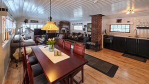 A spacious living area with a wooden dining table, a kitchen with a brick wall, and a cozy seating area with a sofa and armchairs. - Gorgeous home in Flatdal with sauna (Flatdal)