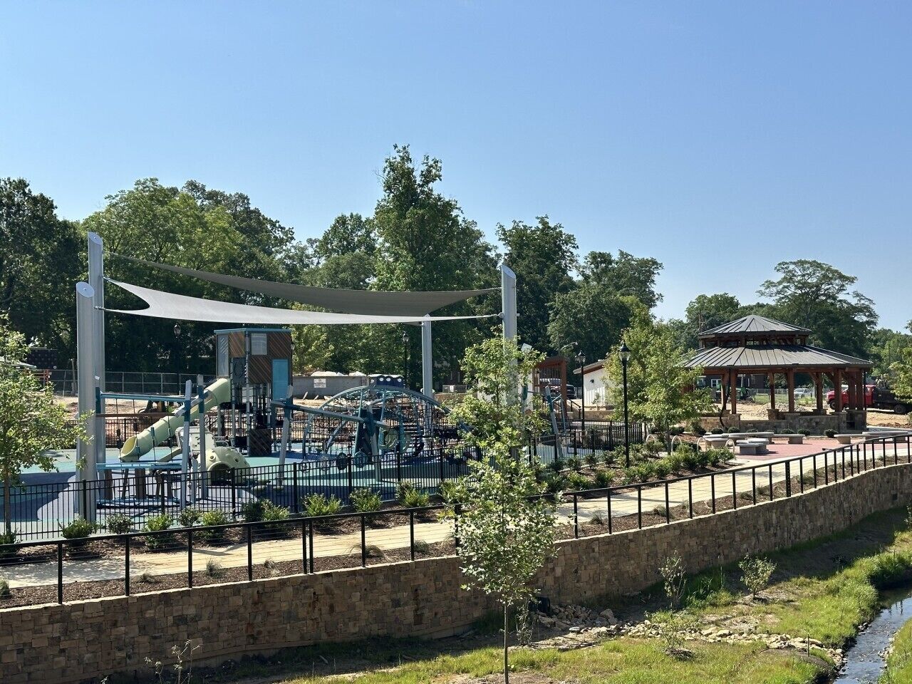 A playground with various play structures, a covered seating area, and a small pavilion.