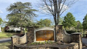 Una entrada de pedra amb un rètol que diu 'LINLEY PARK ANDERSON', envoltada d'una zona enjardinada amb flors.