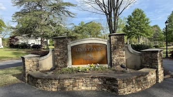 A stone entrance with a sign reading 'LINLEY PARK ANDERSON' surrounded by a landscaped area with flowers.
