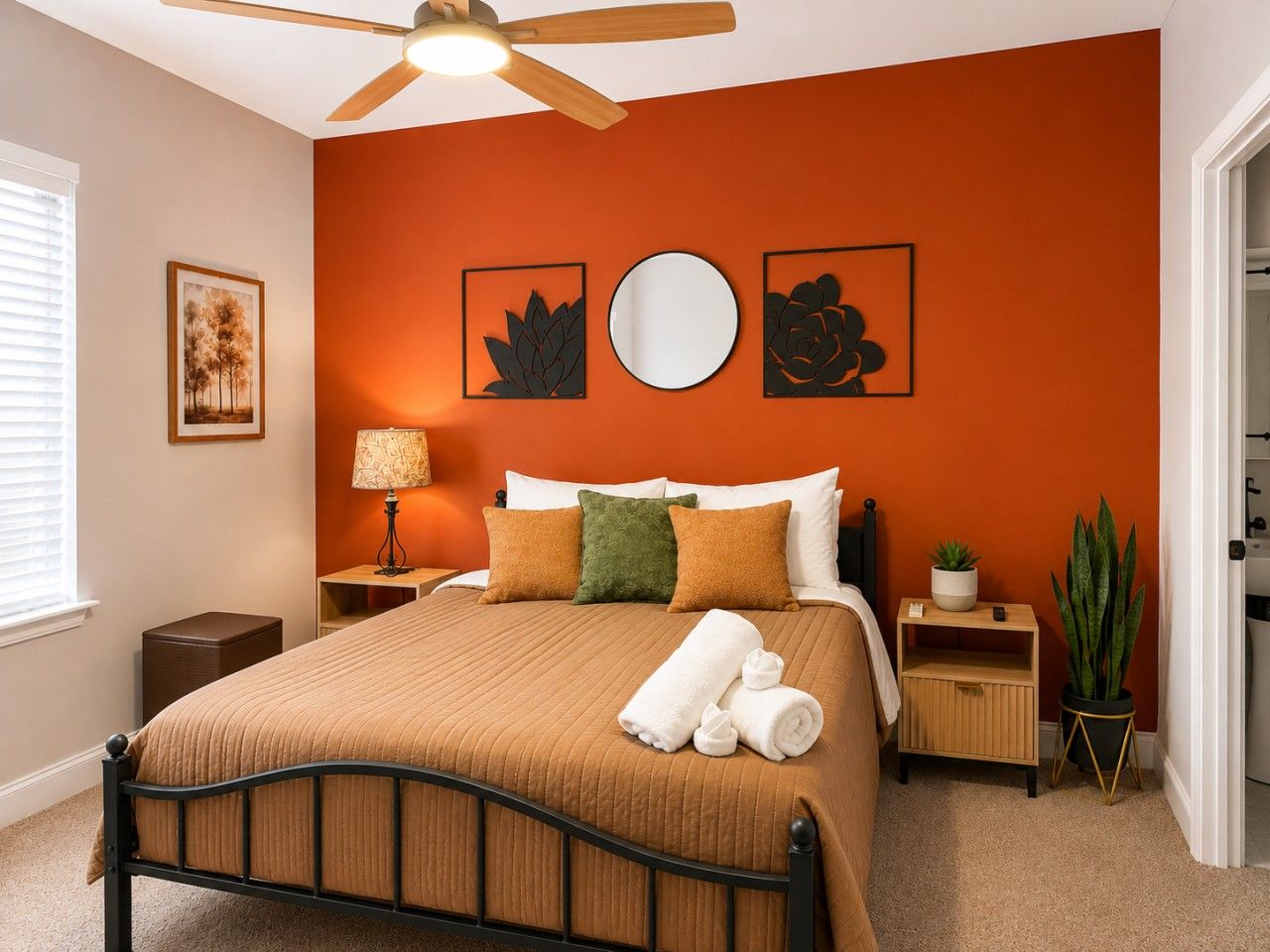 A bedroom with a bed, a nightstand, a lamp, a potted plant, and artwork on the wall.