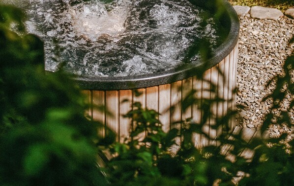 Ein runder Springbrunnen im Freien mit Holzrand und Kiesbett.
