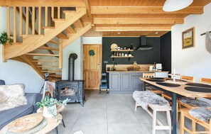 Ein gemütliches Interieur mit einer Holztreppe, einer Küche mit grauen Schränken und einem Essbereich mit Tisch und Stühlen.