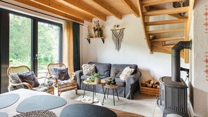Un salon chaleureux avec un canapé, des fauteuils, une table basse et un poêle à bois.