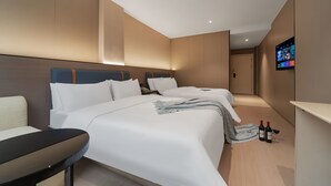 Una habitación de hotel moderna con dos camas, un televisor de pantalla plana y un miniibar.