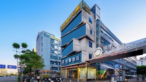 Un hotel con fachada moderna, un letrero llamativo y un estacionamiento con motocicletas.