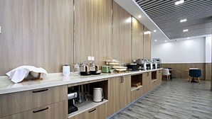 Un área de cocina moderna con electrodomésticos integrados, una encimera larga y una zona de estar con sillas.