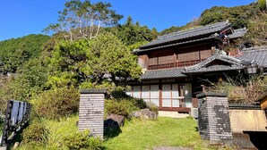 A traditional Japanese house with a tiled roof, wooden structure, and a stone entrance gate. - Up to 10 persons! The large porch overlooks the garden and the bamboo grove to the south over the rare armrest balustrade. (須崎市)